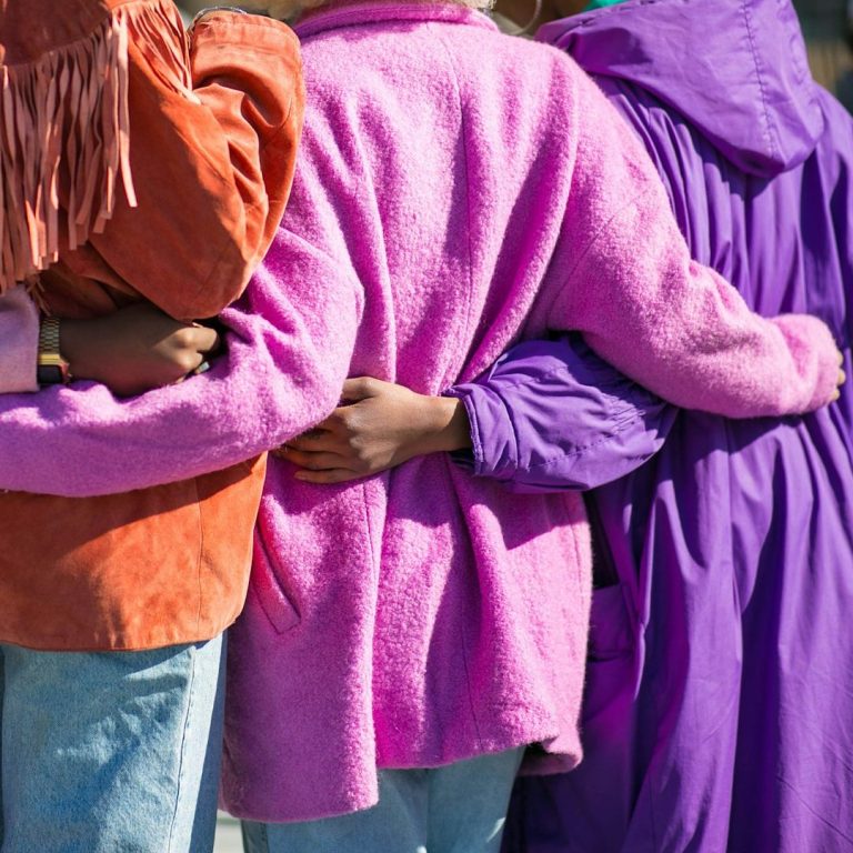 Gruppierung von Personen in bunten Jacken, die sich um die Schultern legen.
