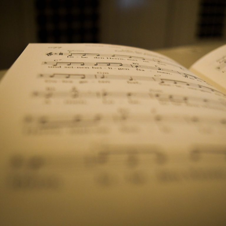 Notenblätter mit Musiknotation, unscharf im Vordergrund, Hintergrund verschwommen.